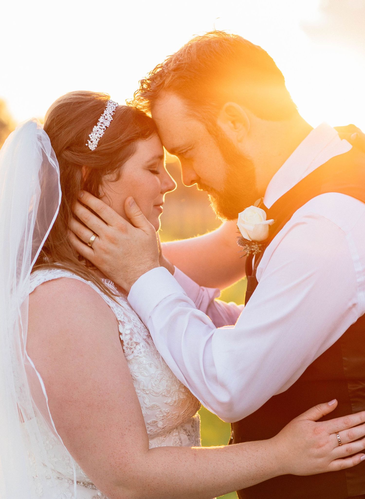 Bride and groom sharing an intimate moment bathed in warm golden sunset light.