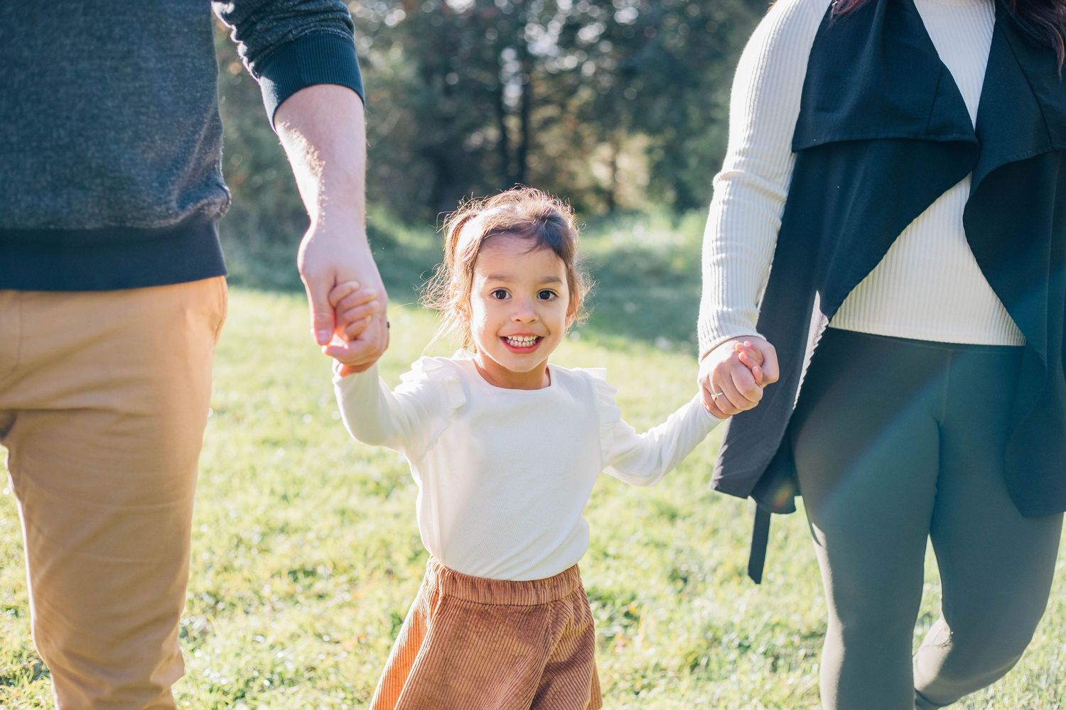 Girl holding hands with her parents and smiling in Stratford Ontario