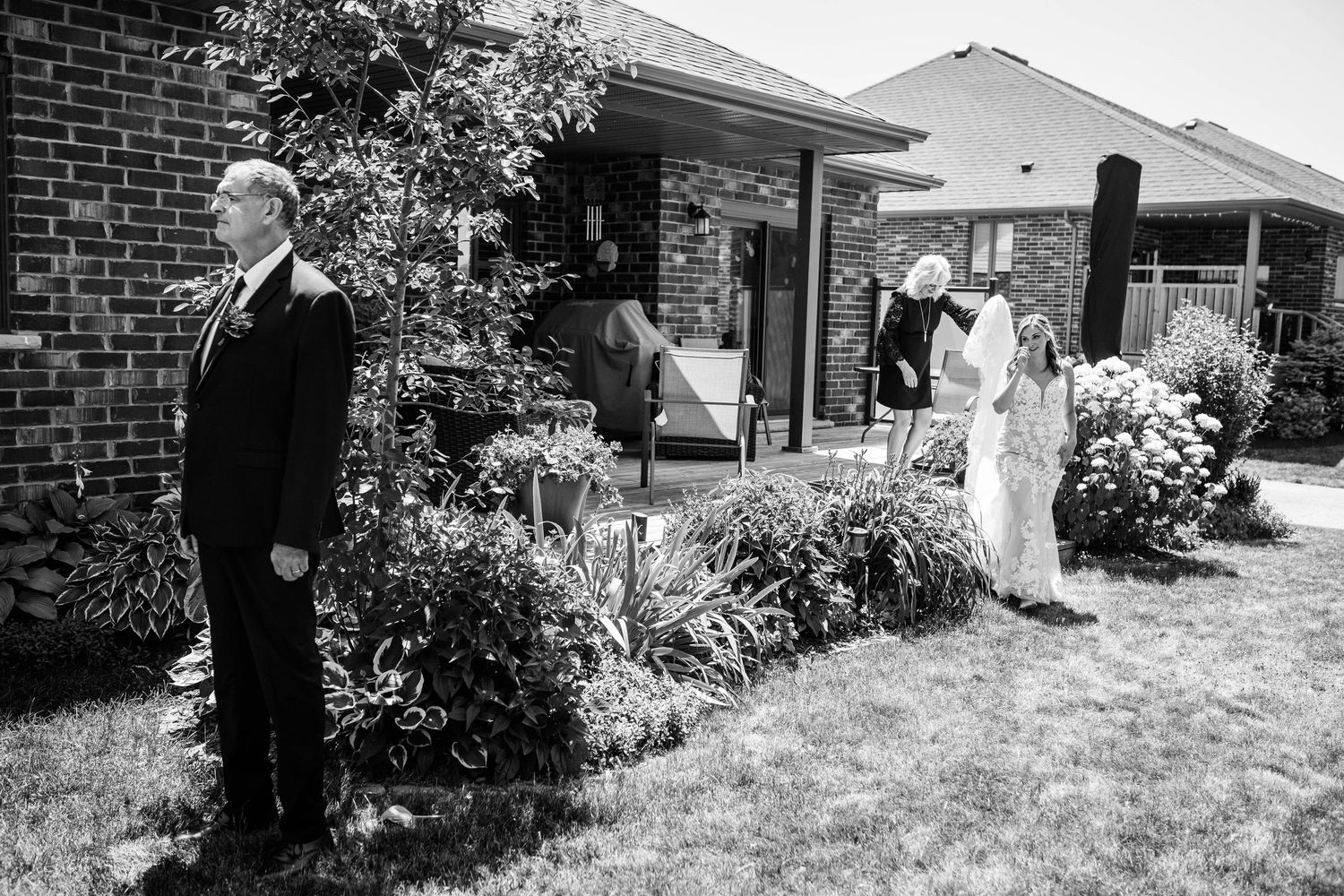 Black and white photo of a bride sharing a first look moment with her father outside the family home.