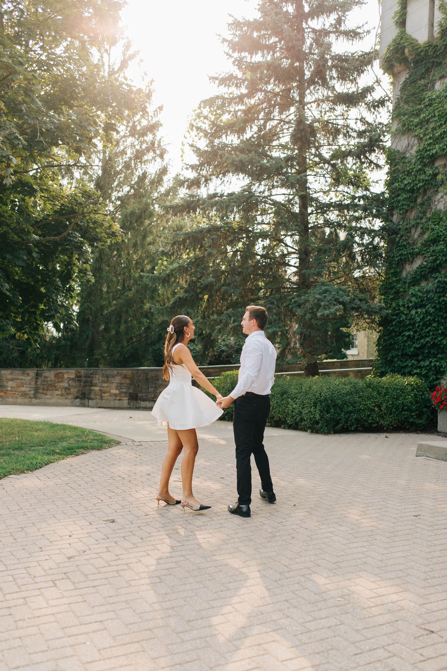 Bride and groom playing around with each other during golden hour on a brick path in London Ontario