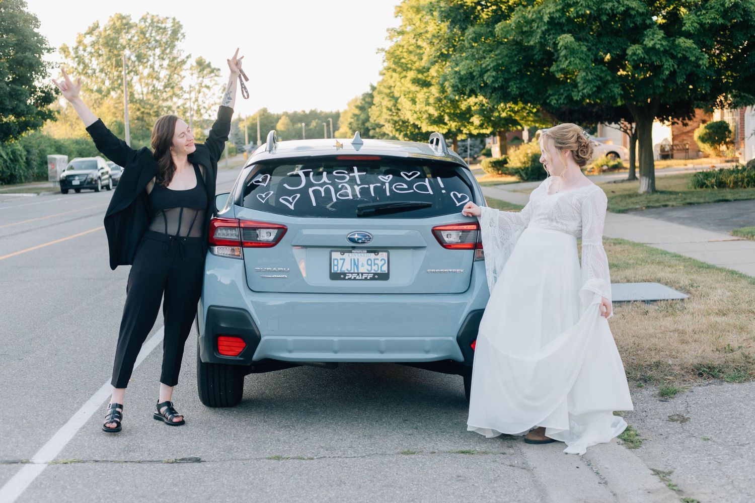 Just married lesbian couple posing by a car with Just Married written on the window.