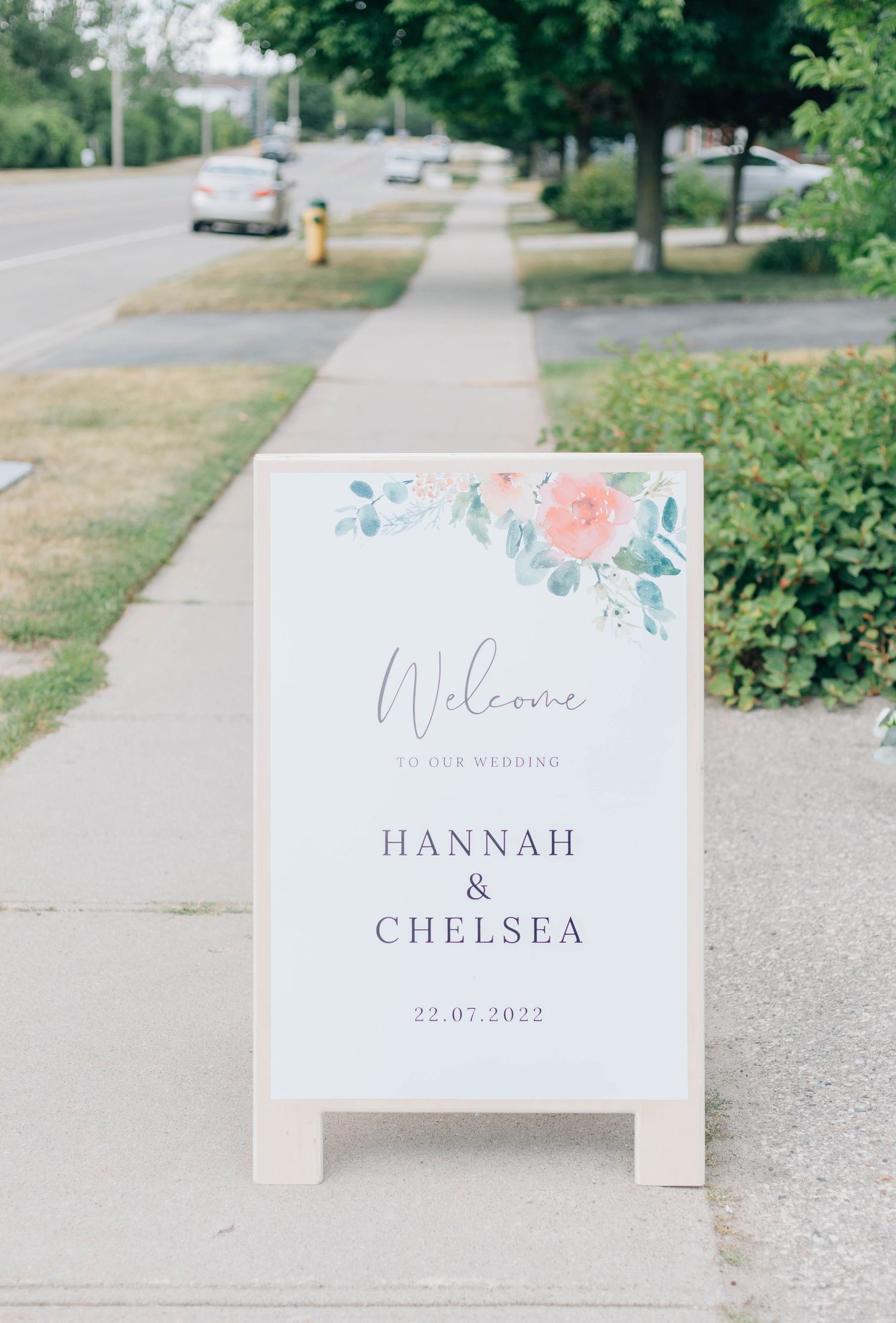 Elegant outdoor wedding welcome sign for Hannah and Chelsea dated 22.07.2022 with floral watercolor design.