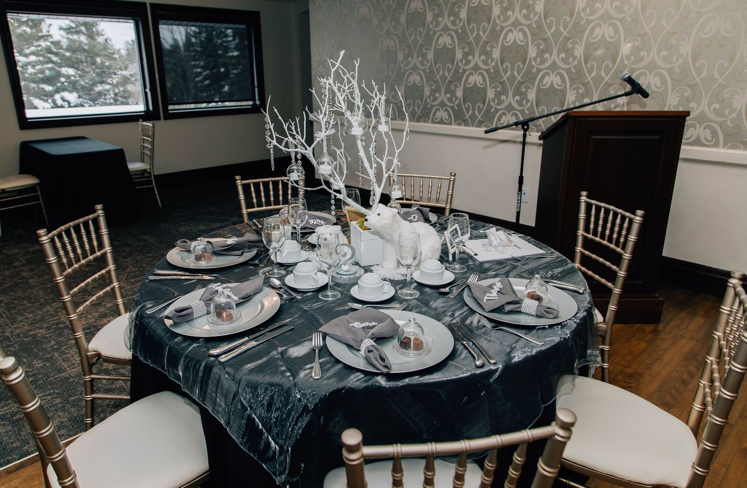 Winter wedding round table with dark velvet linen, white branch centerpiece, and gold chiavari chairs in a damask room.