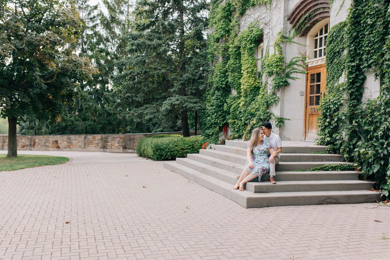 Couple sitting on stone steps outside ivy-covered building in London Ontario