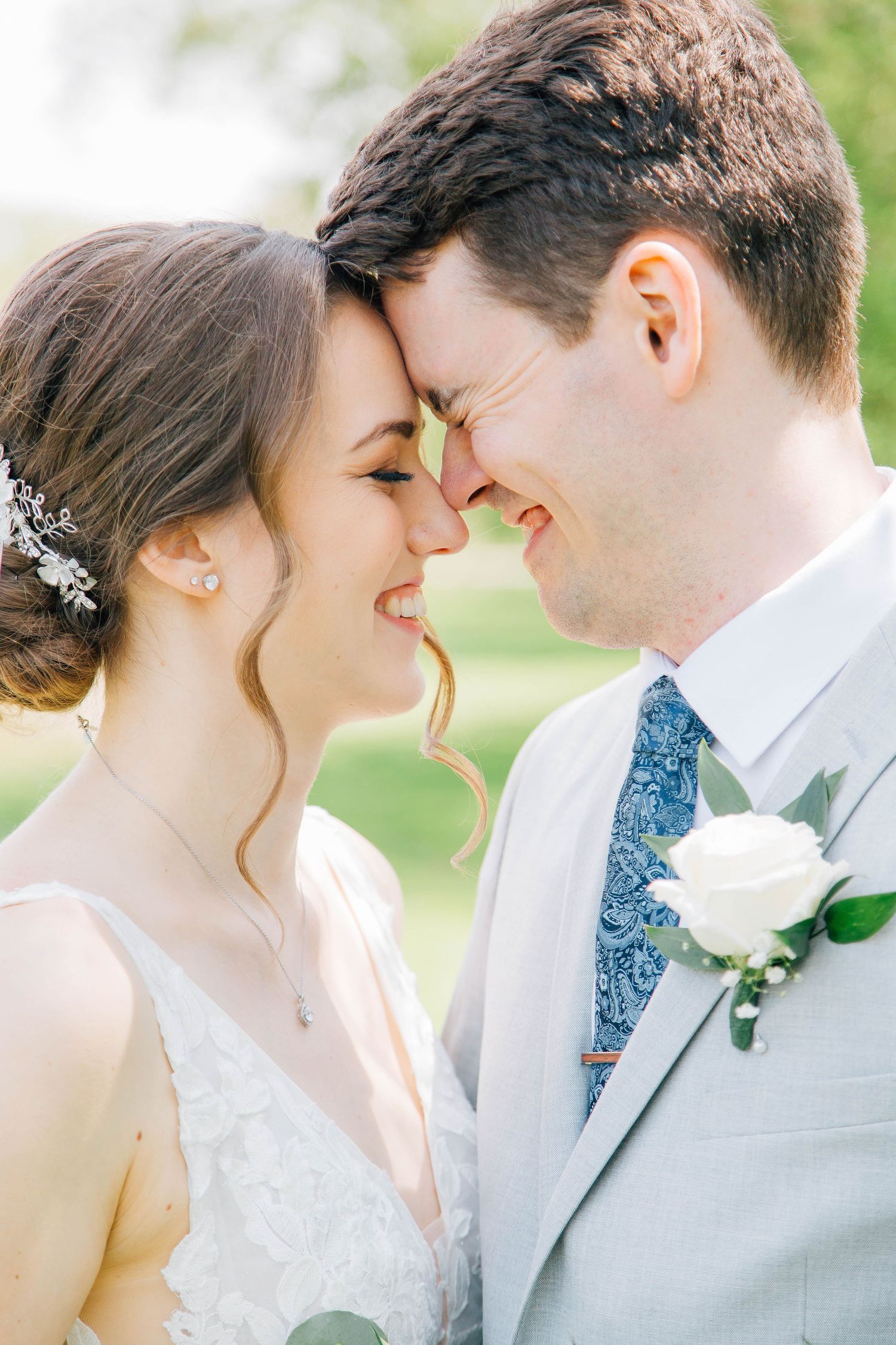 Bride and groom touch foreheads and smile joyfully in close romantic wedding portrait.