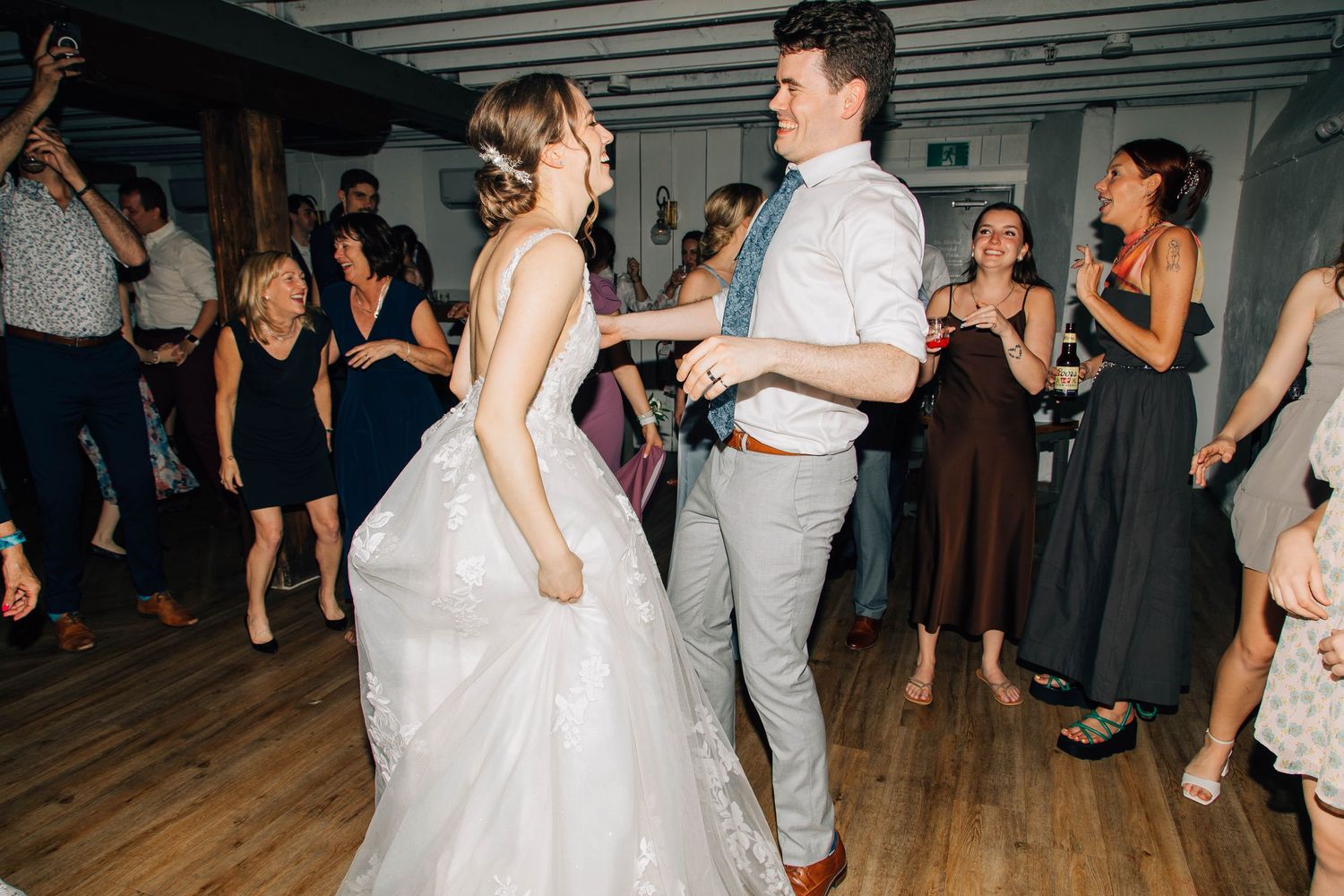 Bride in white gown and groom in gray suit share a romantic dance at their reception.
