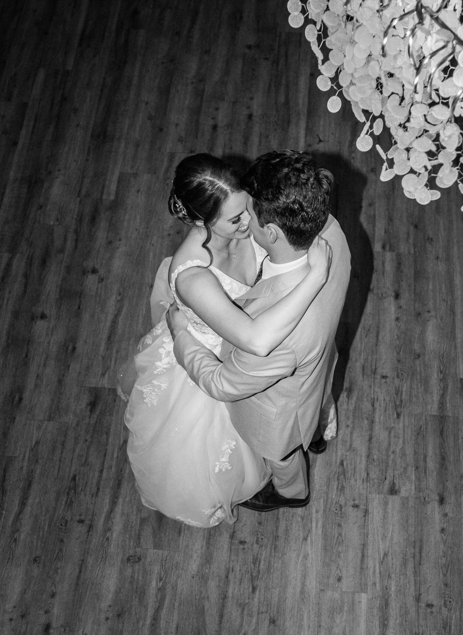Aerial black and white view of bride and groom sharing their romantic first dance together.
