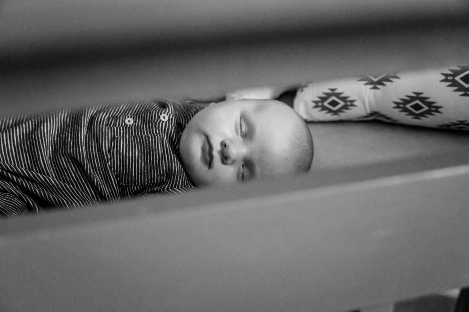 Black and white photo of a sleeping newborn baby lying in a crib.
