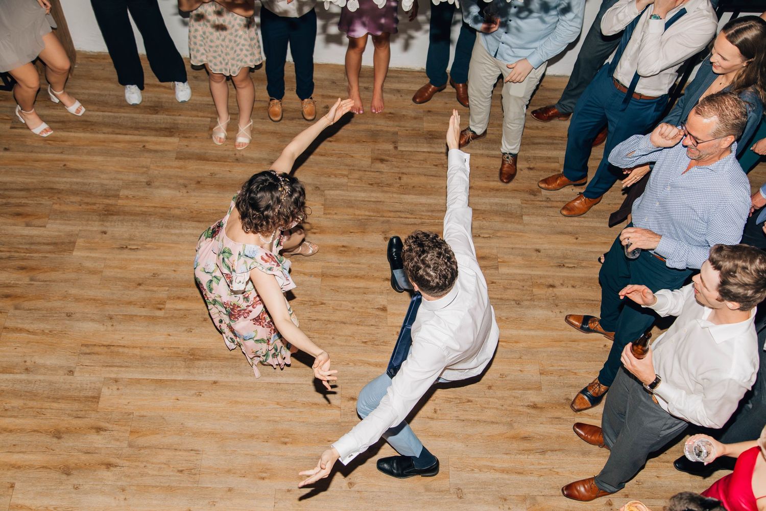 Two guests perform an energetic dance move on the wedding reception dance floor.