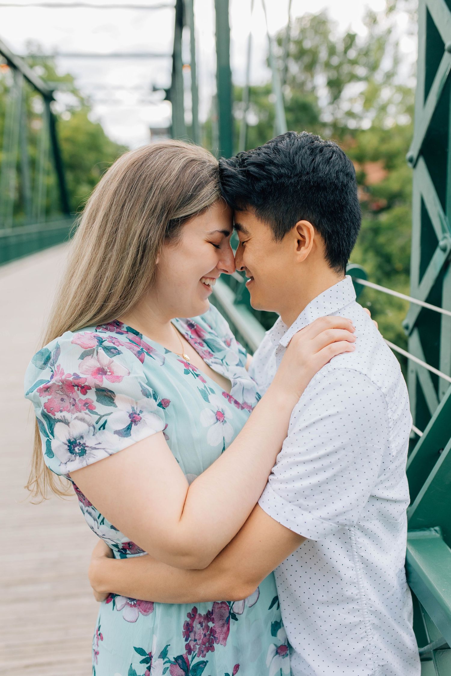 engaged couple getting close and touching foreheads on a bridge in london ontario
