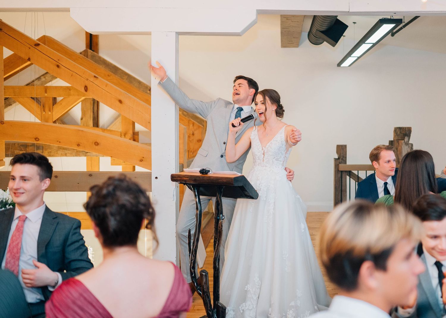 Bride and groom singing joyfully at a microphone during their wedding reception celebration.