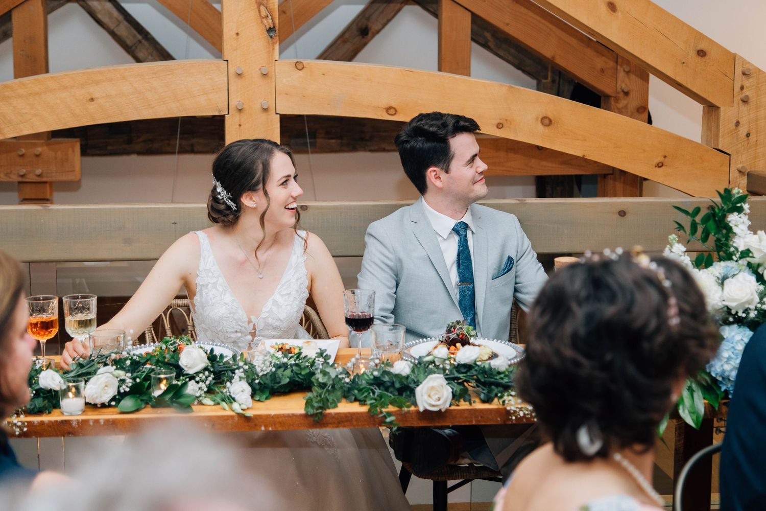 Bride and groom sharing a joyful moment at their decorated sweetheart table at reception.