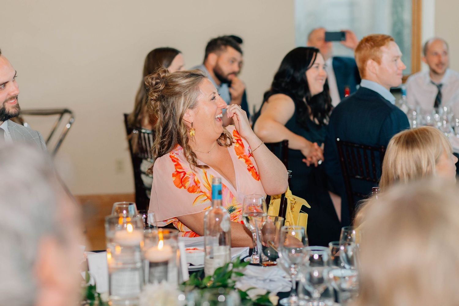 Guests laughing and enjoying themselves during a wedding reception dinner at elegantly decorated tables.