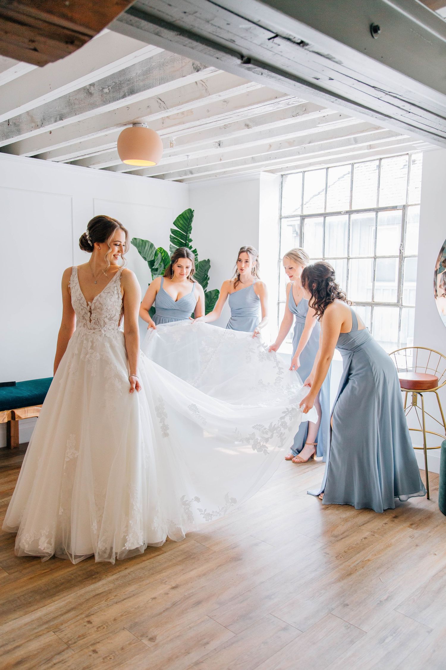 Bride and bridesmaids fixing bride's dress at The Timber Barn in St. Jacob's, ON