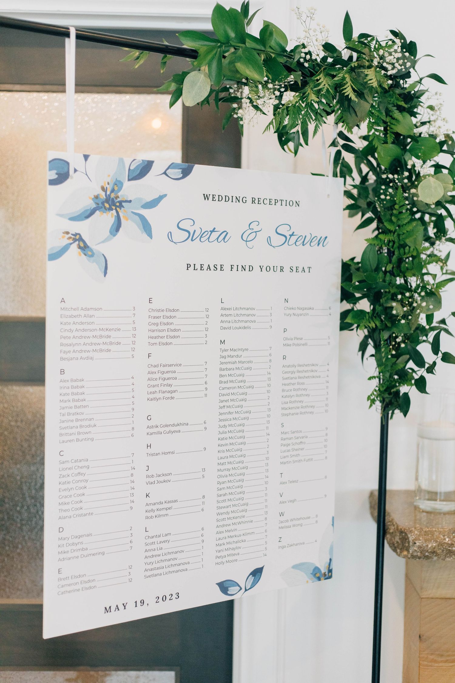 Wedding reception seating chart for Sveta and Steven dated May 19, 2023, with blue floral decor.