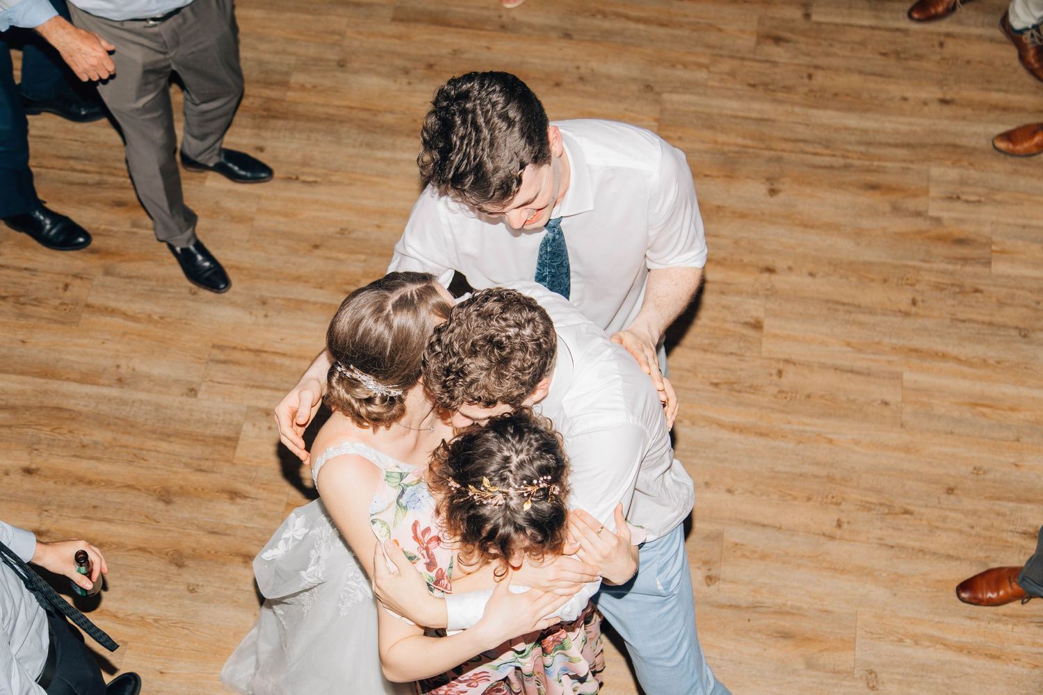 Small group of wedding guests share a warm group hug on the dance floor.