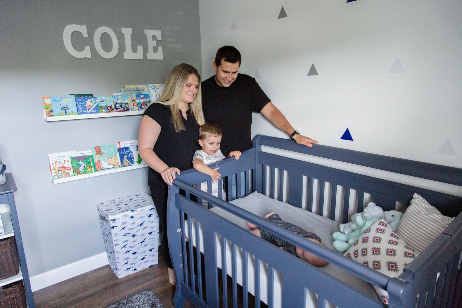 Parents admire their baby boy Cole in his navy blue nursery crib.