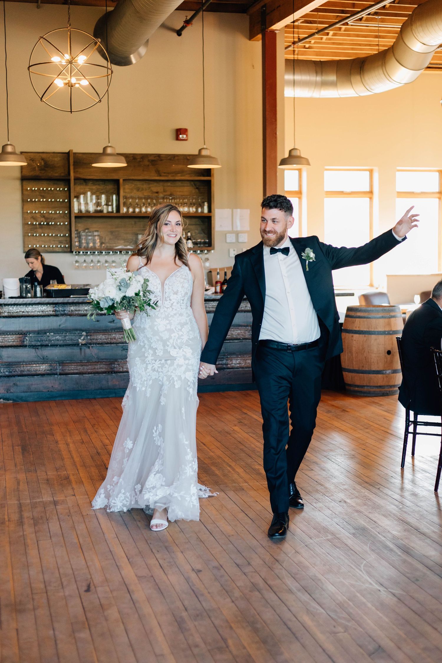 Bride and groom in tuxedo make a joyful grand entrance at their wedding reception at Rivers Edge at the Arlington in Paris Ontario.