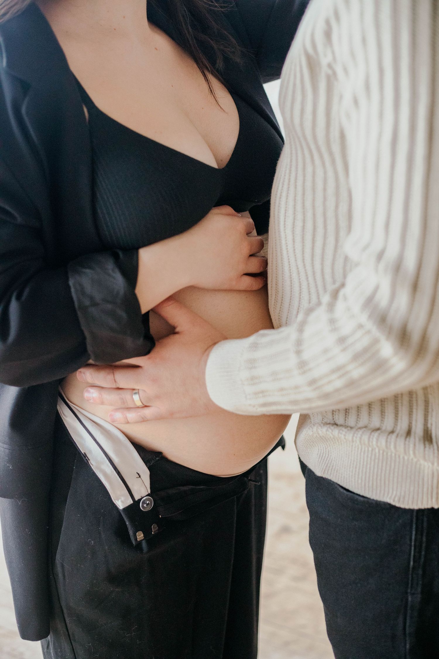 Close-up of couple tenderly holding pregnant belly during intimate maternity session.