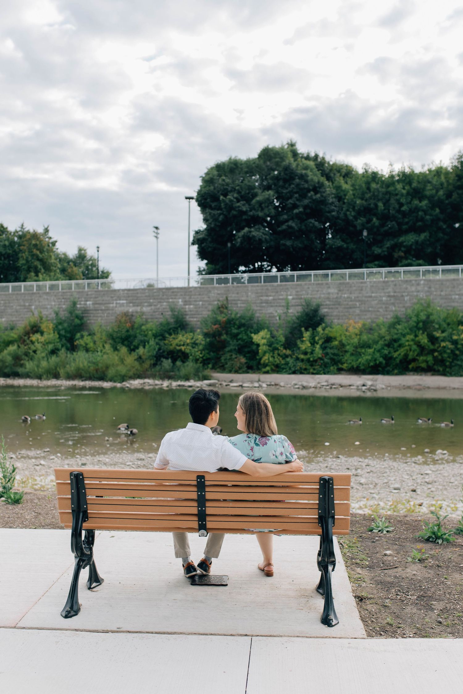 couple sitting on bench gazing out at the water at harris park in london ontario