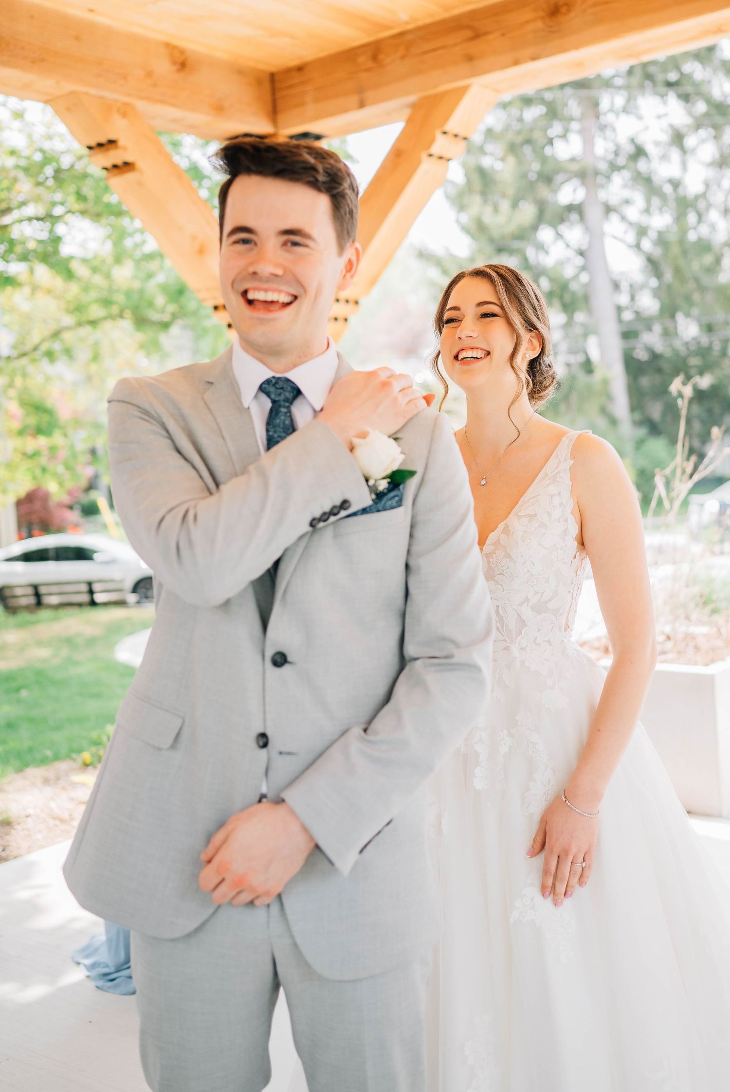 Happy bride and groom share joyful first look moment under wooden pavilion at The Timber Barn in St. Jacob's Ontario.