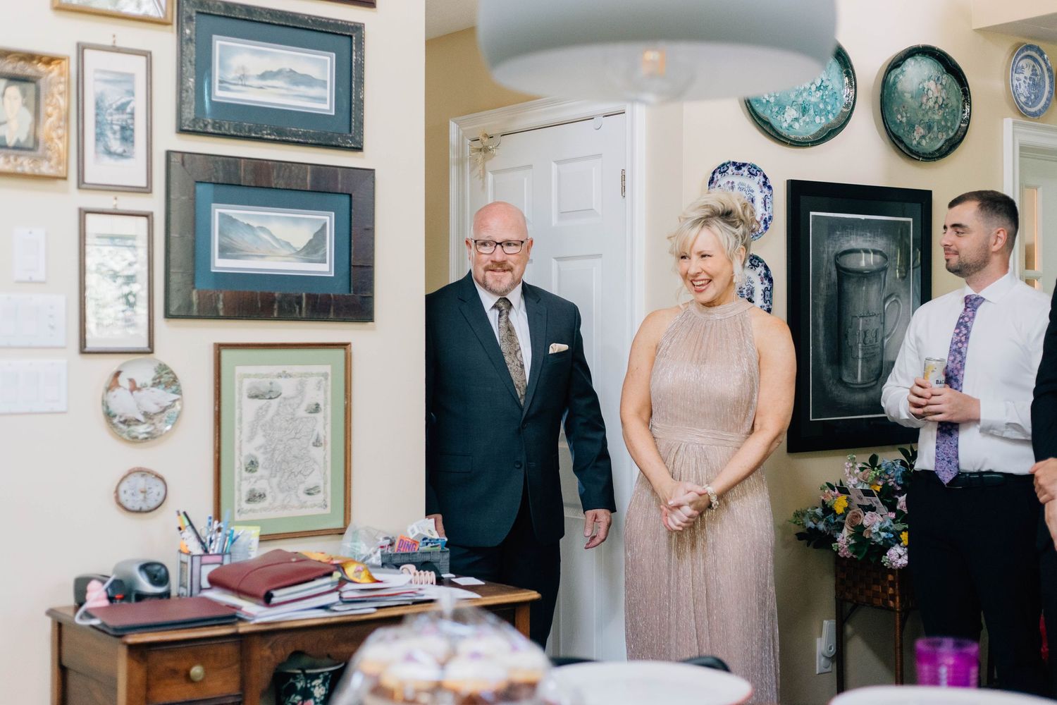 A man in a suit and a woman in a pink dress smiling in a decorated home office.