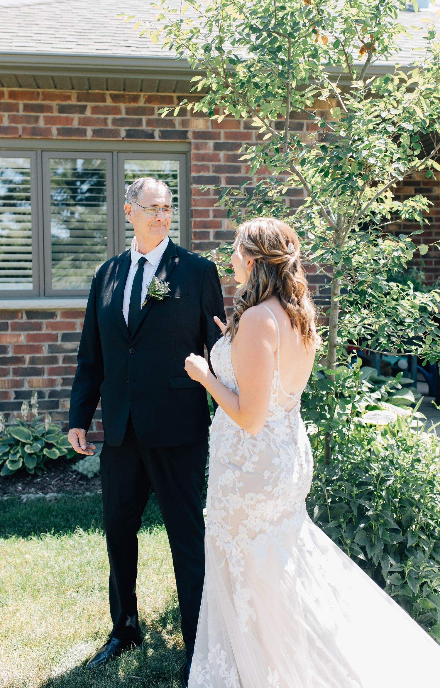 Father in black suit sees his daughter in a lace wedding gown for the first time outside the family home in New Hamburg.