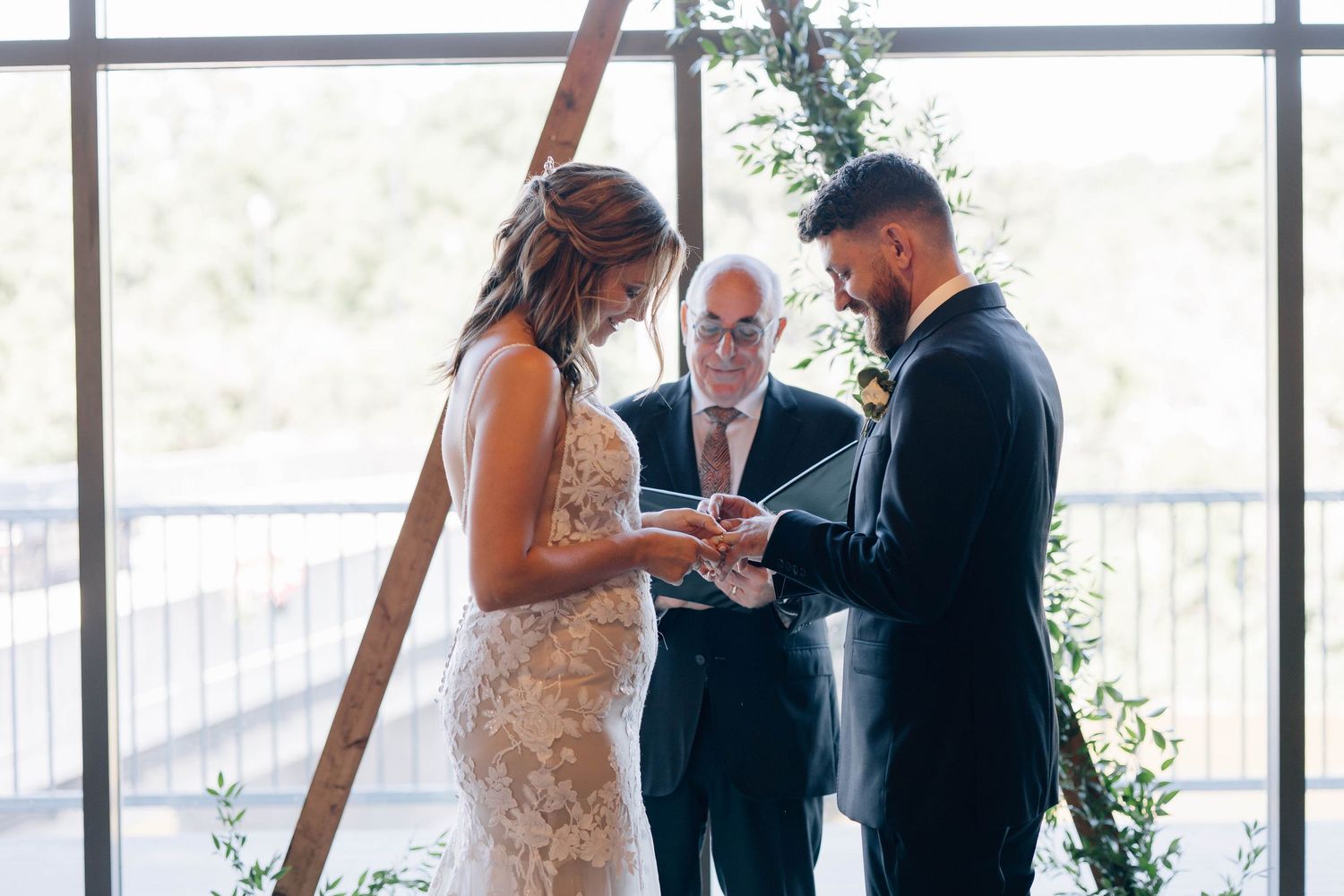 Bride and groom exchanging rings at altar with officiant during wedding ceremony.