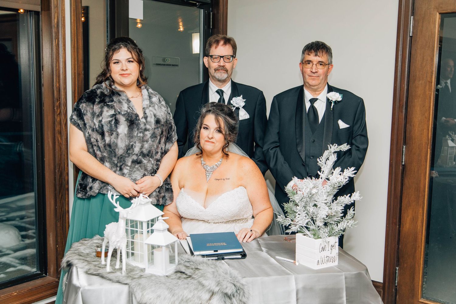Wedding party poses at signing table with white lanterns and winter floral decorations after ceremony.