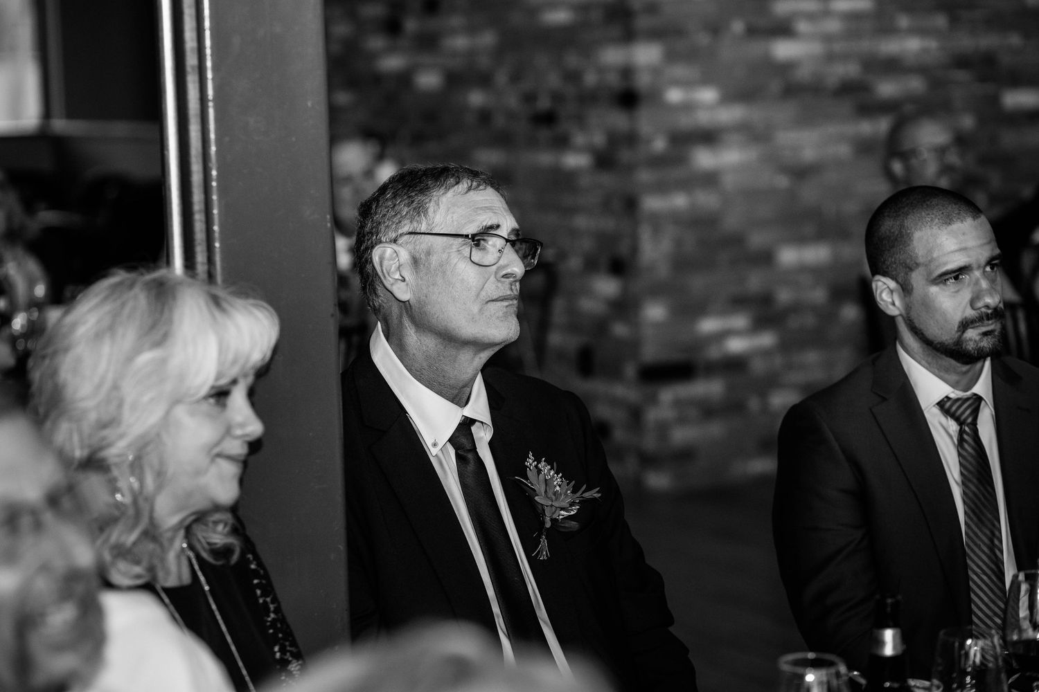Black and white photo of wedding guests attentively watching ceremony proceedings.