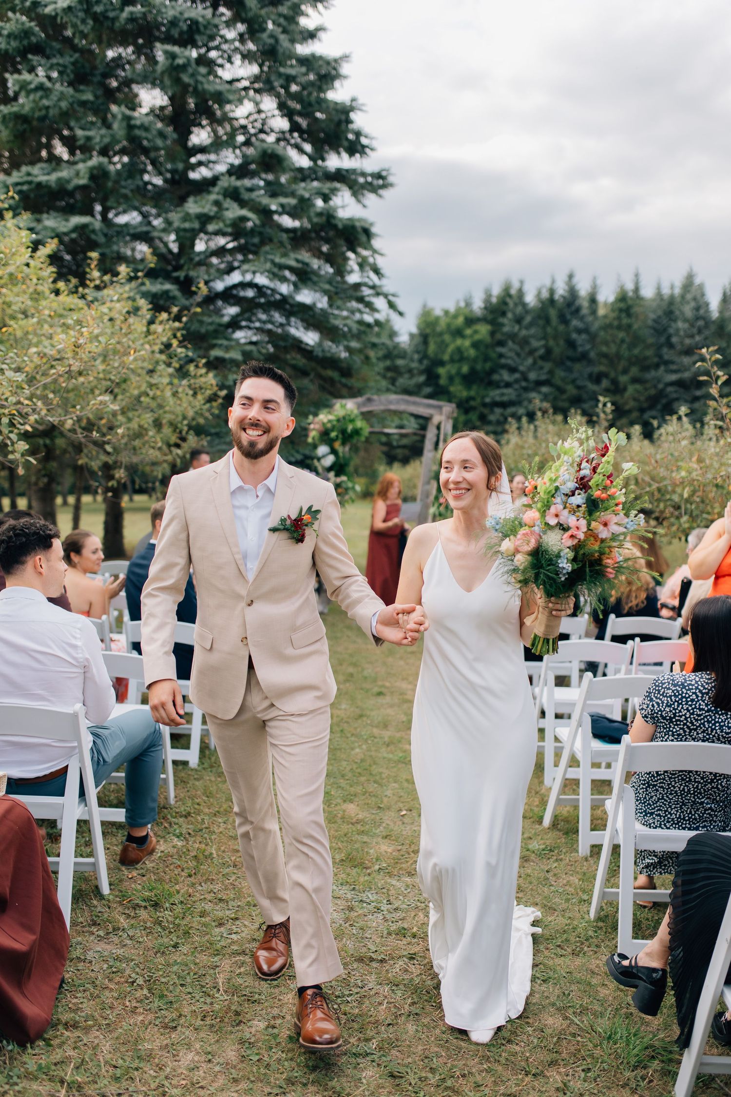Newlyweds walking back down the aisle hand in hand at an outdoor garden wedding ceremony.