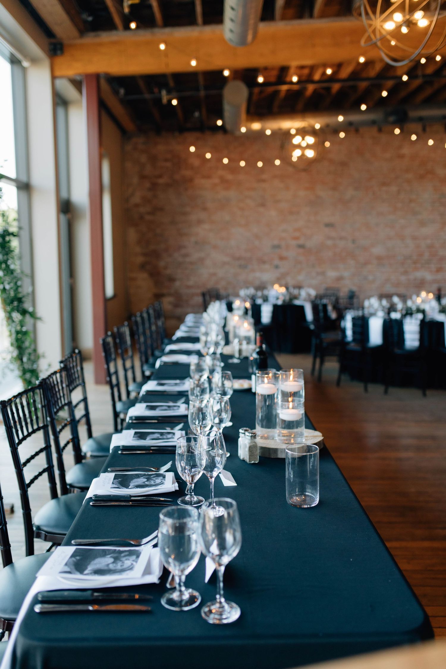 Elegant wedding reception with long dark tables, candles, and string lights at Rivers Edge at the Arlington in Paris Ontario.