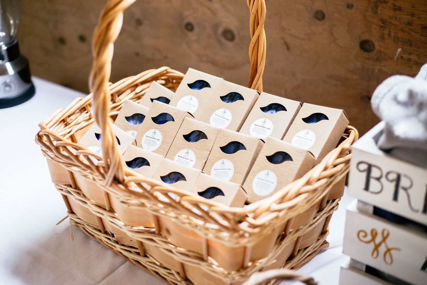 Wicker basket filled with kraft paper wedding favor boxes with black mustache designs for rustic barn wedding.
