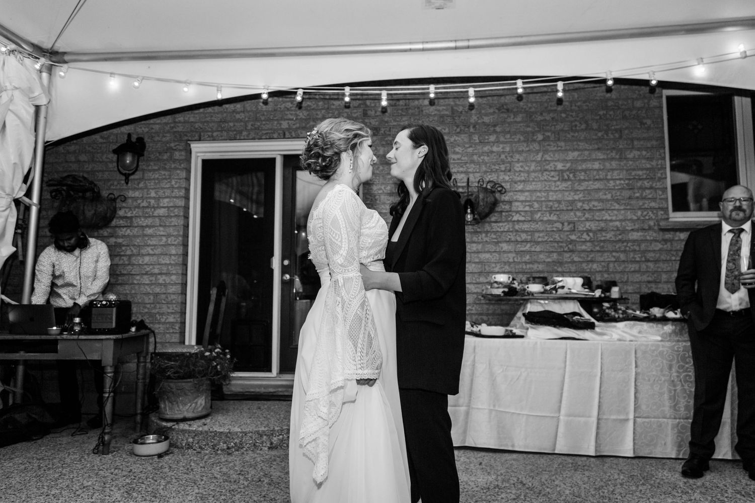 Newlywed couple sharing their first dance at an outdoor wedding reception in black and white.