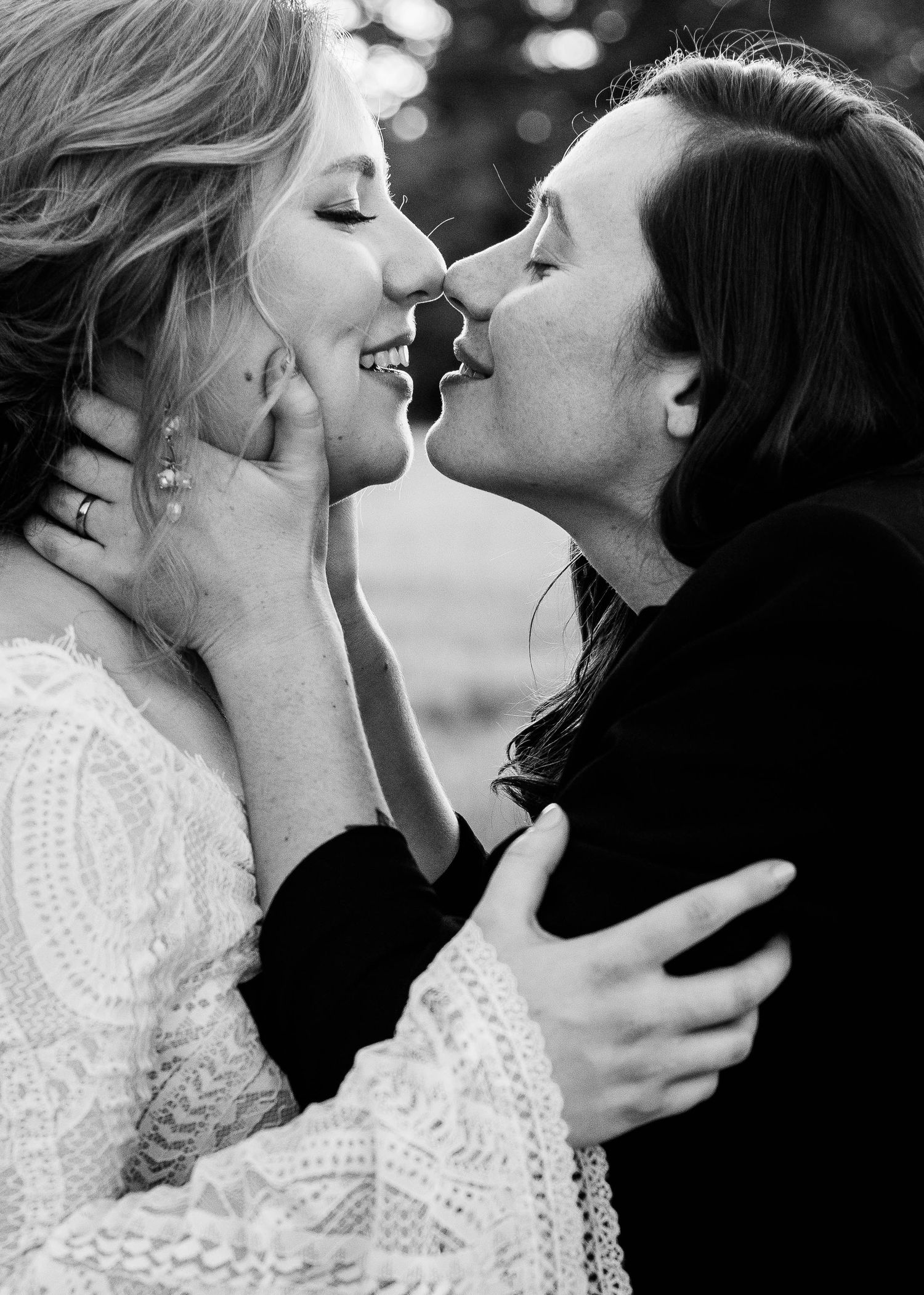 Black and white photo of couple sharing romantic almost-kiss, groom cradling brides face tenderly.