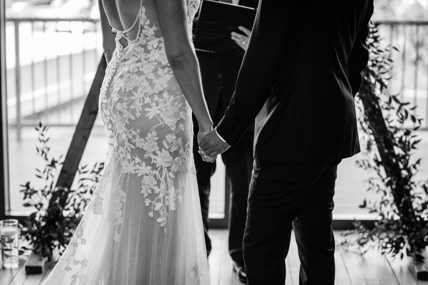 Bride and groom holding hands at altar in black and white wedding photo.