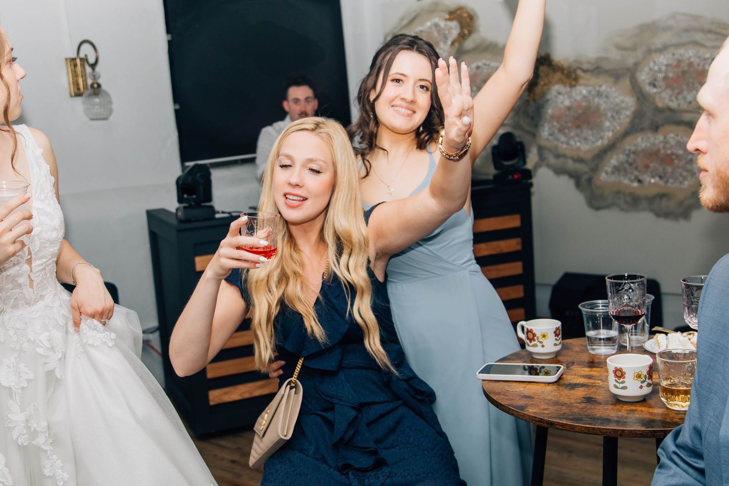 Bridesmaids dancing and celebrating joyfully at a rustic indoor wedding reception party.