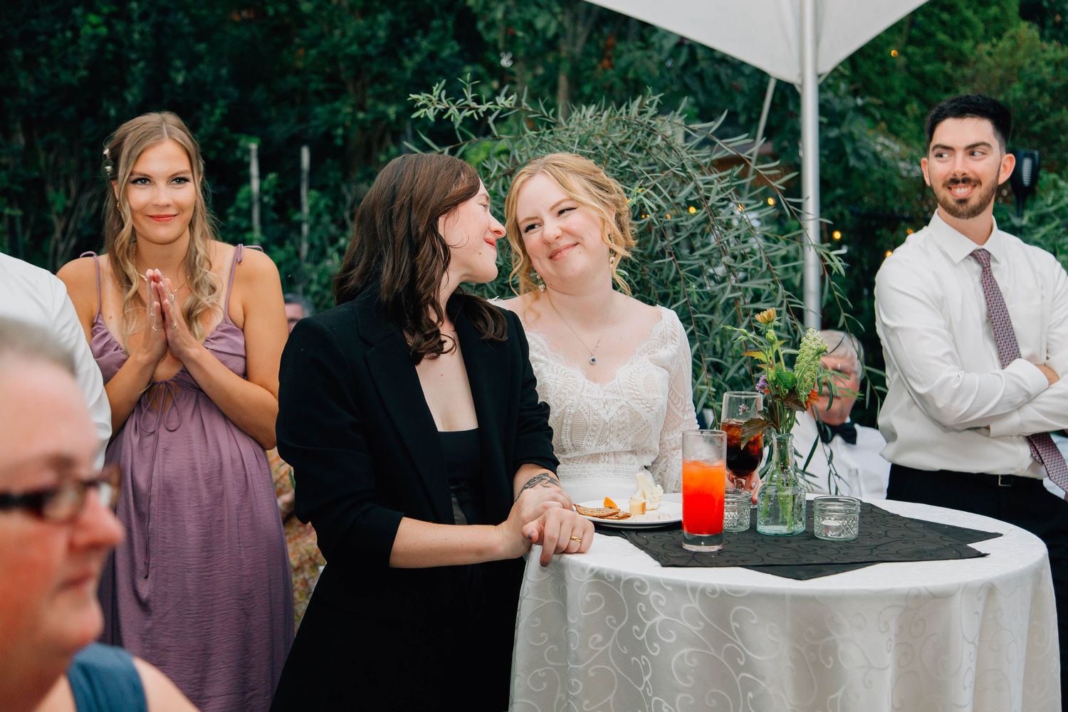 Bride in white dress shares a joyful moment with guest at outdoor wedding reception.