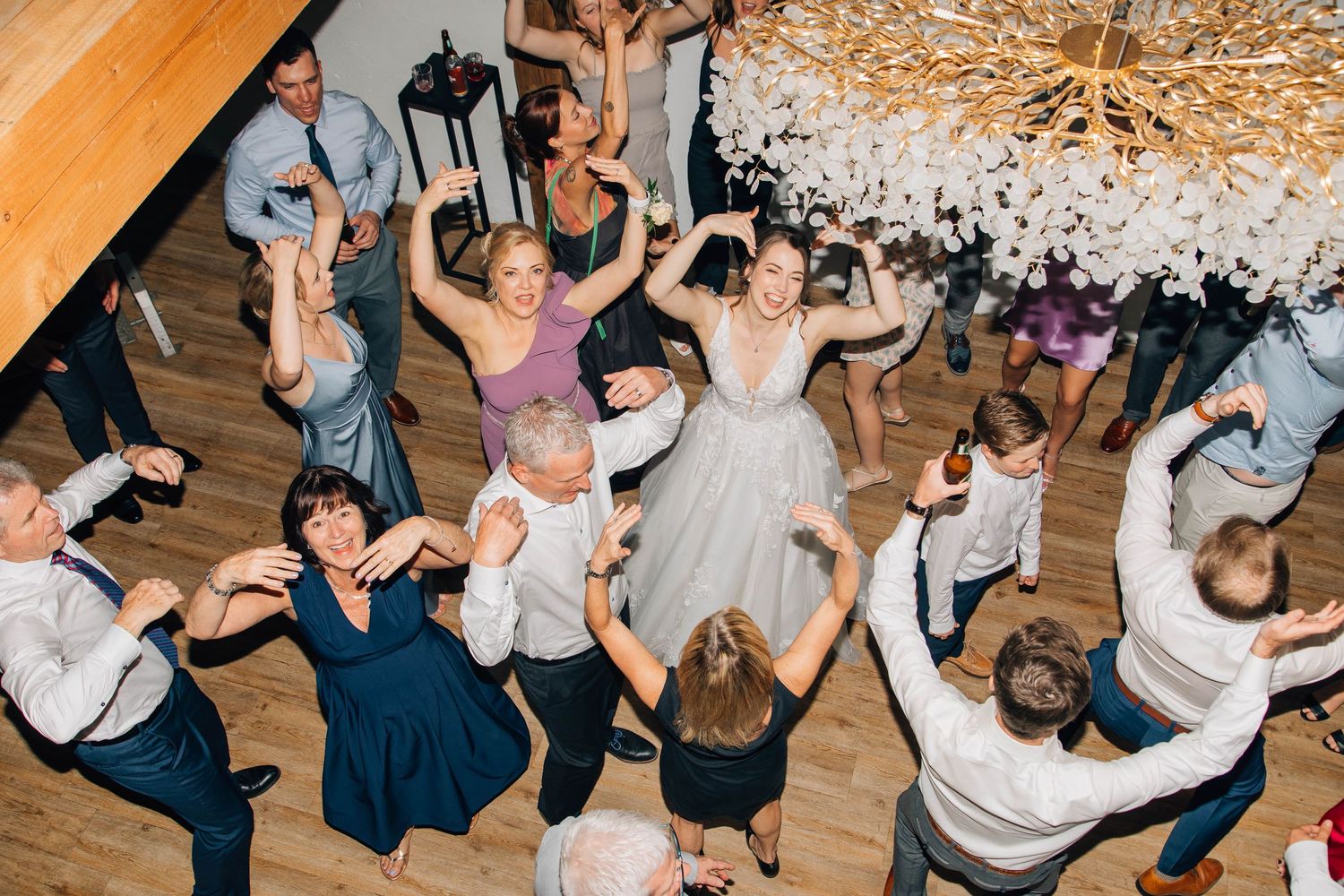 Aerial view of bride and wedding guests dancing joyfully together on the dance floor.