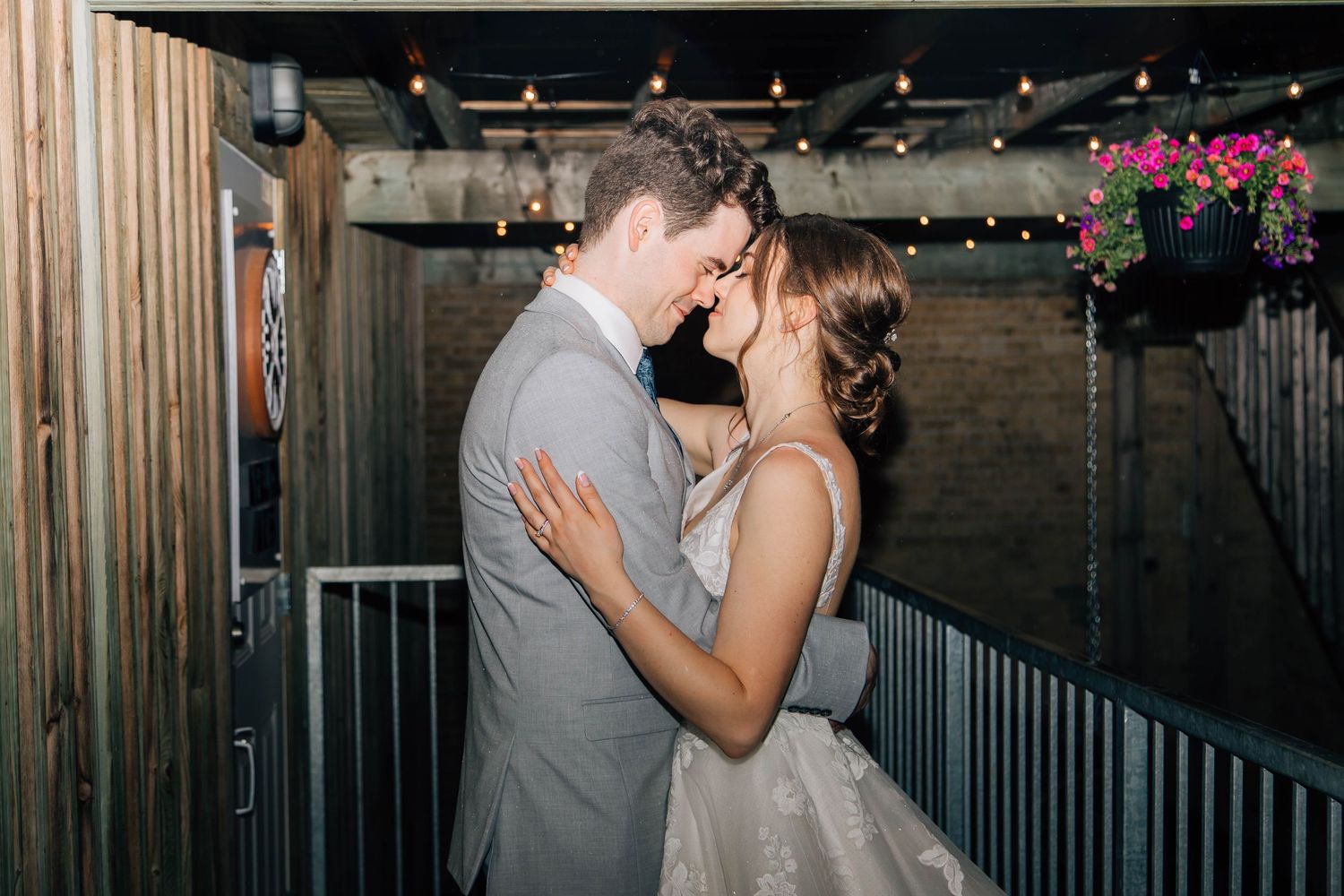 Bride and groom sharing a romantic forehead touch on a balcony with string lights at night.
