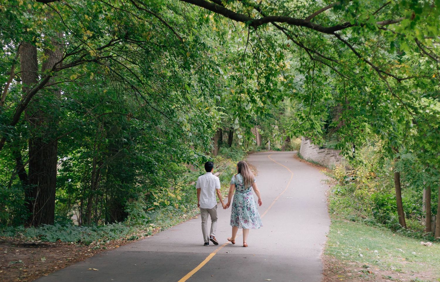 Couple walking away down a trail surrounded by lush trees