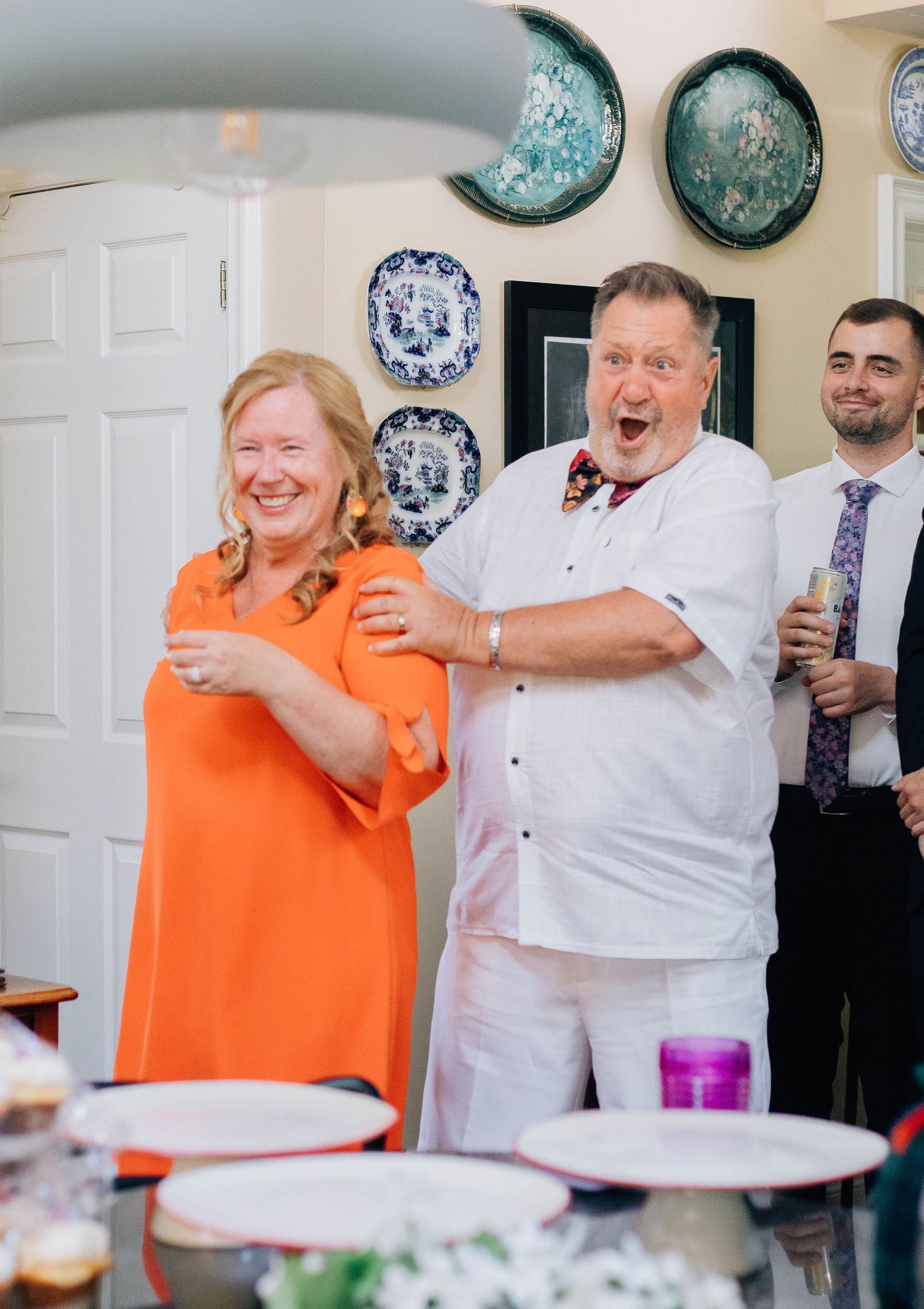 A joyful couple in festive attire laughing together at a wedding reception indoors.