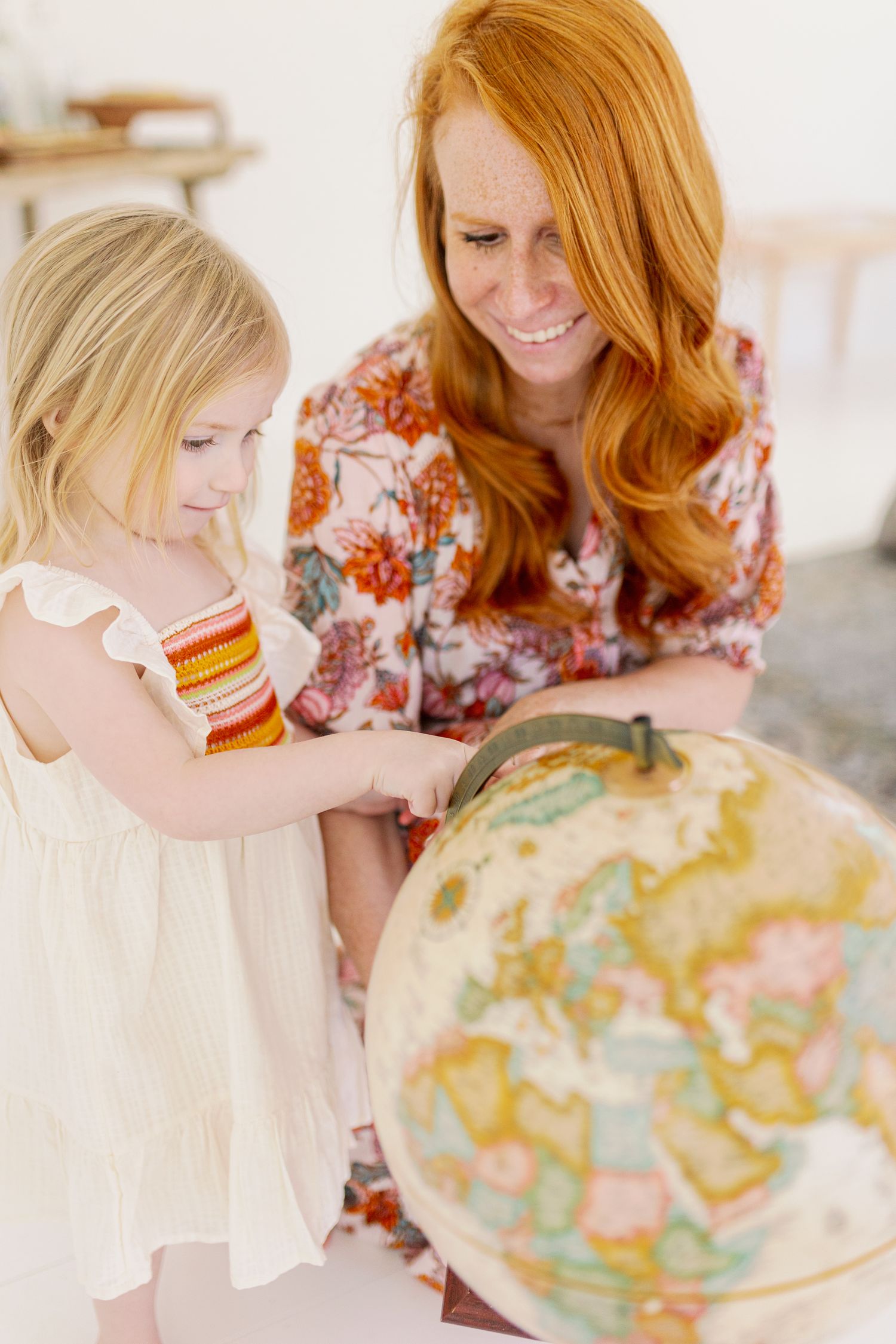Two people looking at and pointing to a world globe together in a light-filled room.