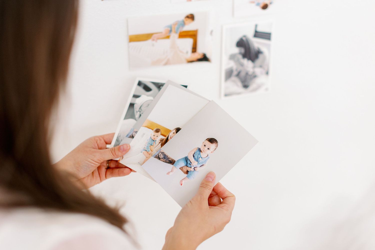 Someone holding printed photographs in their hands against a white background.