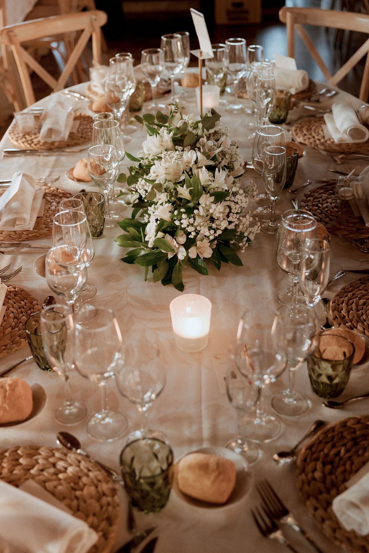 Elegant wedding reception table set with white flowers, candles, and glassware.