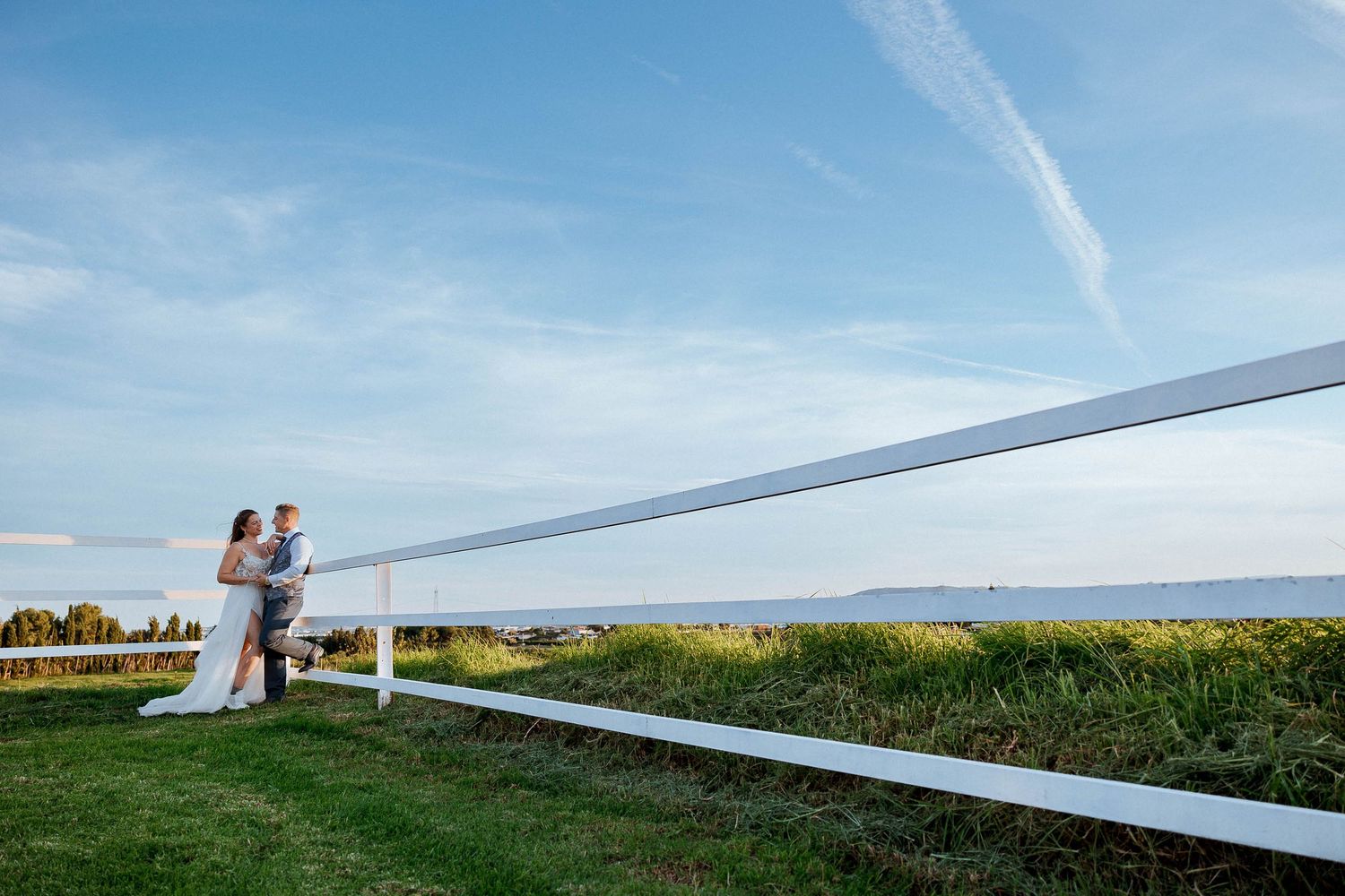 A couple stands together against a scenic mountain backdrop during a romantic outdoor wedding photoshoot.