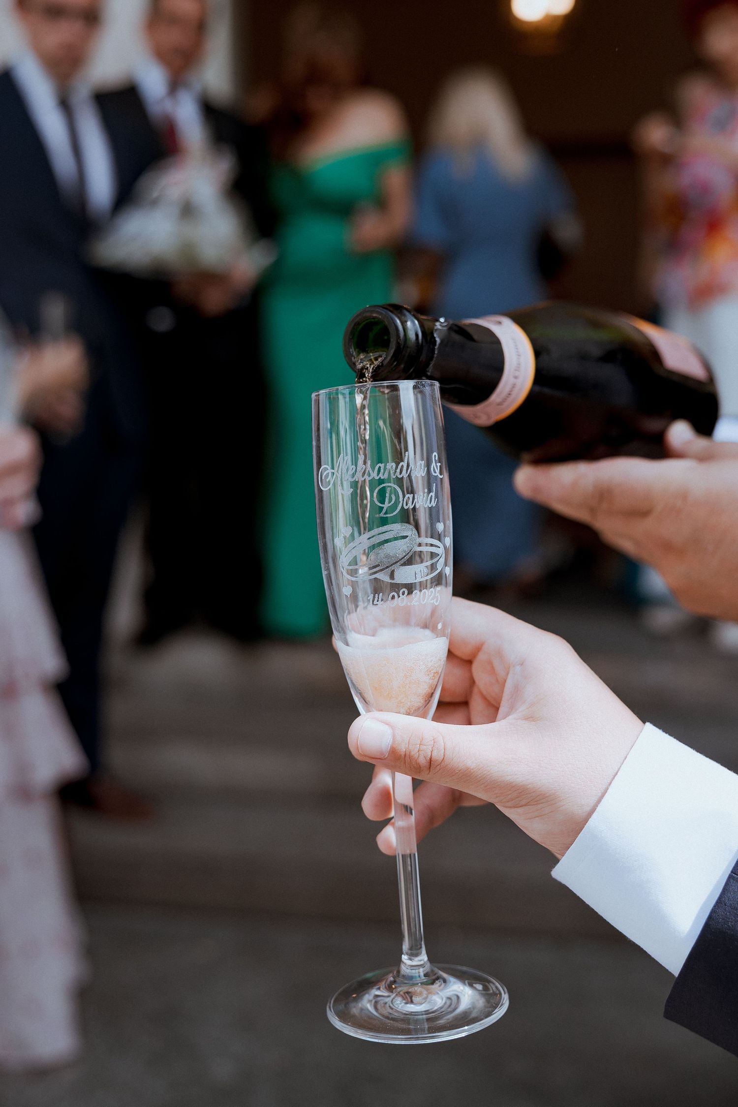 Champagne being poured into an engraved wedding flute at a reception celebration.