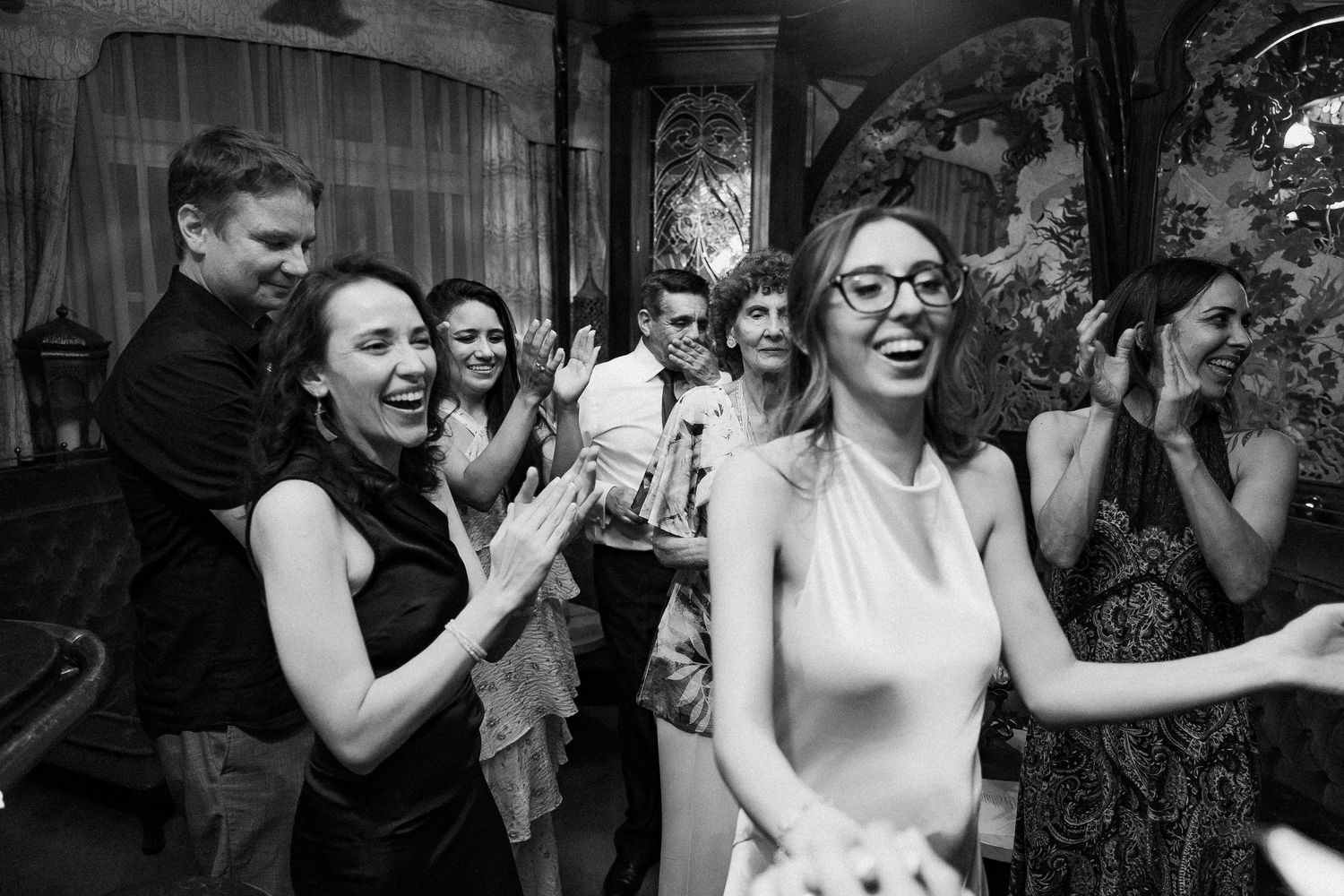 Bride laughs joyfully with guests dancing and celebrating at lively black and white wedding reception party.