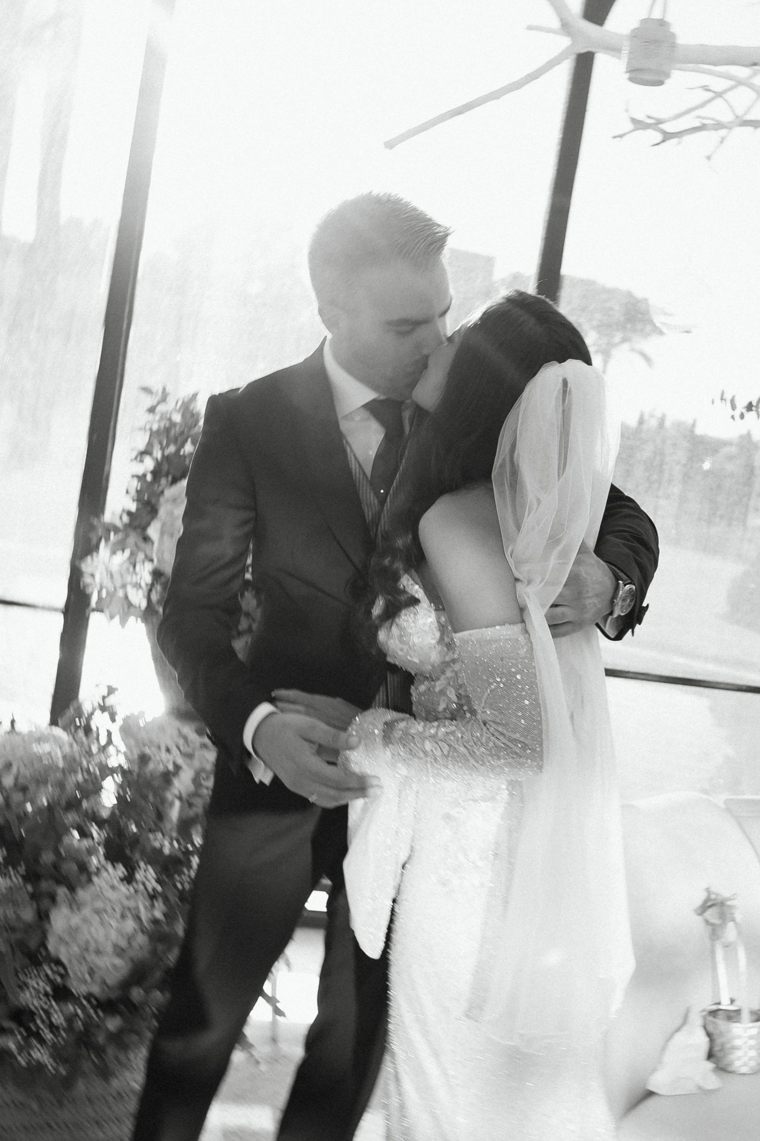Black and white photo of newlyweds sharing a passionate kiss during wedding ceremony.