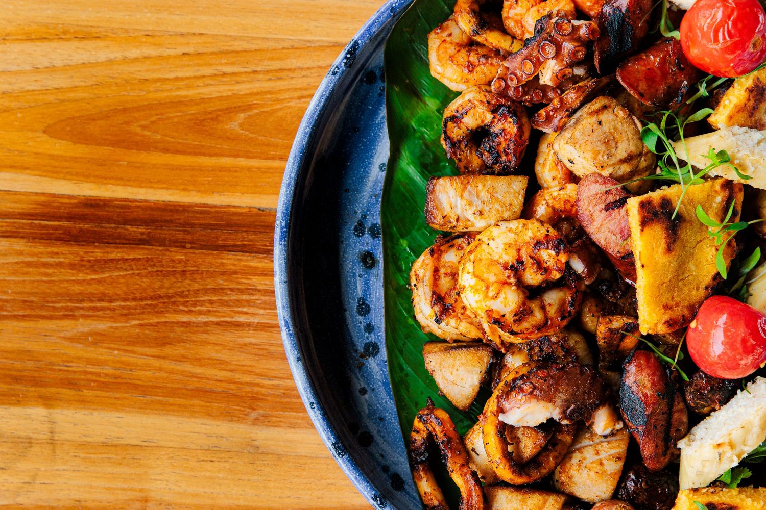Stir-fried chicken and vegetables with mushrooms in a cast iron pan on a wooden surface.
